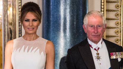 Melania Trump wears a white sleeveless dress with bouffant hair while King Charles wears a tuxedo