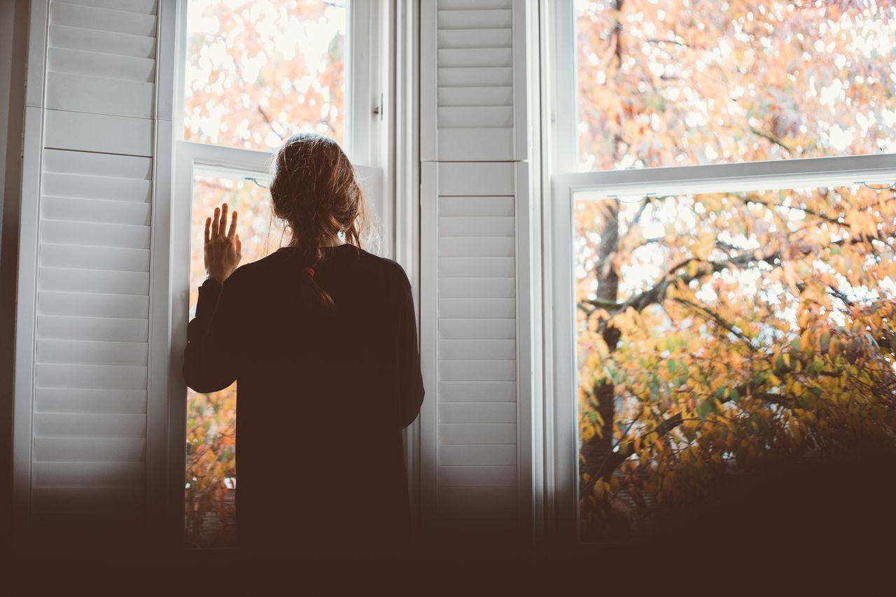 A woman looking through the window. Social distancing