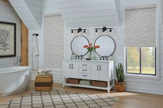Patterned roller shades in bedroom with white dressing tables and mirrors