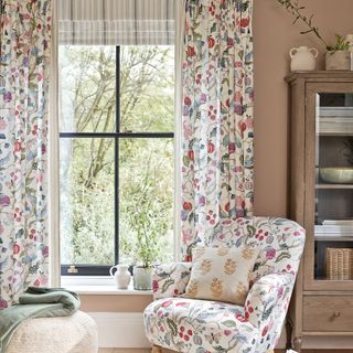 white and pink patterned curtains and matching armchair on wooden floor with grey rug