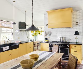 Yellow and white kitchen with black light fixtures and countertops