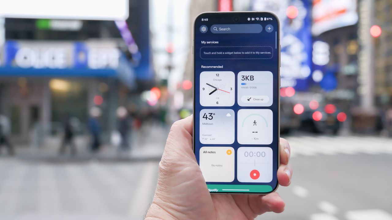 OnePlus 15 in Times Square New York City on the busy street showing the cameras and sides of the phone in addition to home screen panels and Settings menus