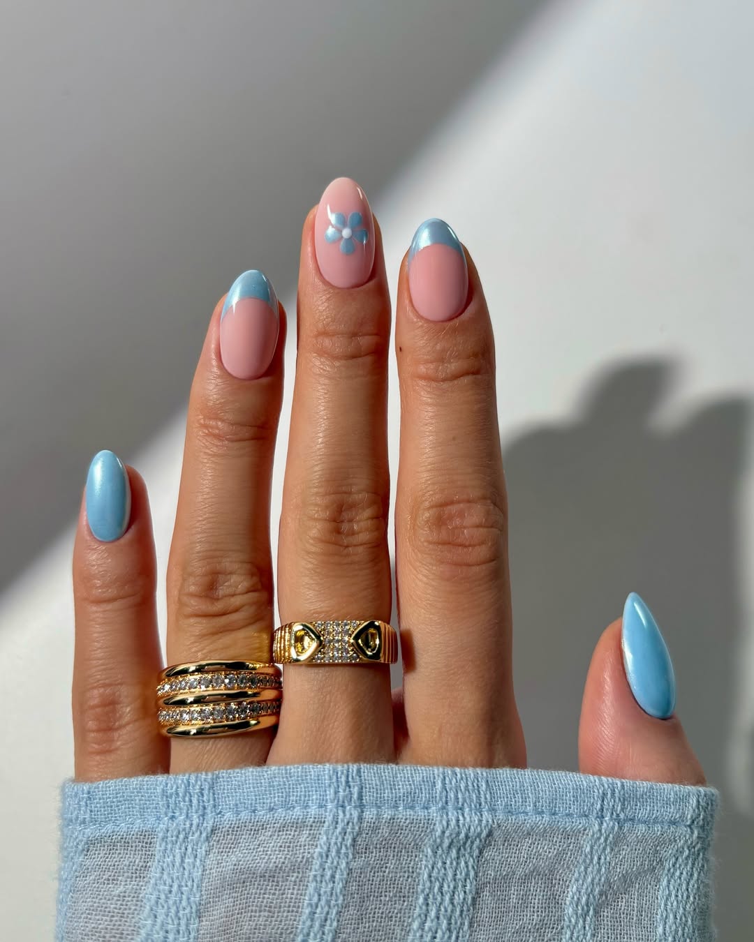 a person wearing light blue chrome nails with a flower design