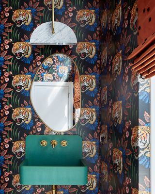 Small powder room with colorful green sink, and Gucci lion-print wallpaper