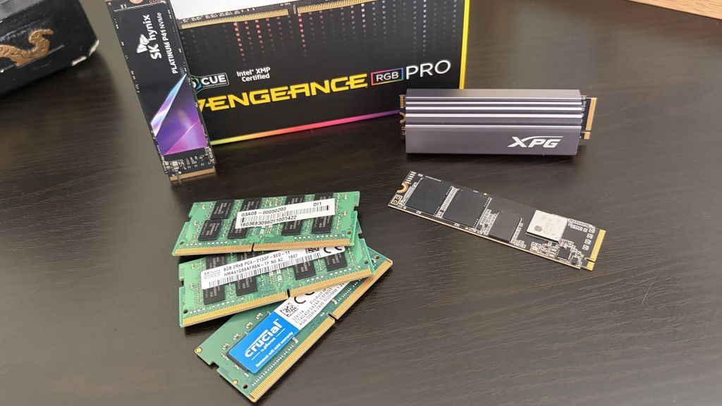 A collection of computer memory components, including green RAM sticks, a silver heatsink labeled "XPG," and a black M.2 SSD.