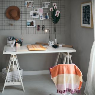 White desk and chair with wire wall decor