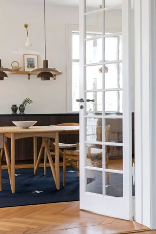 A wooden living area with a table and a navy blue rug