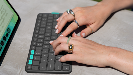 A pair of hands type on the keyboard of the Logitech Flip Folio on a desk.