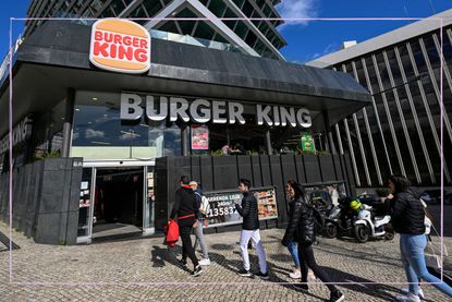 The front of a Burger King store with people walking through the entrance