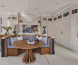 large kitchen with curved floor to ceiling cabinets on one wall, curved island with banquette seating and circular island added to one end of main island