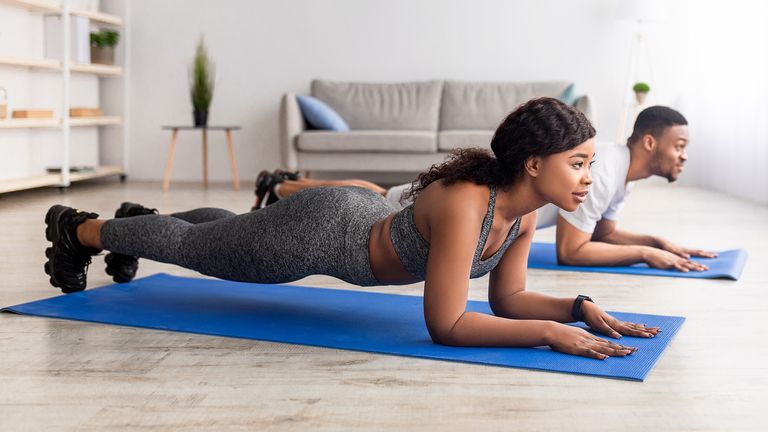 Man and woman doing planks as part of a Pilates workout