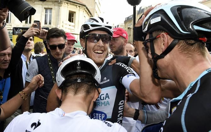 Trentin celebrates his stage 7 win surrounded by his teammates and the press