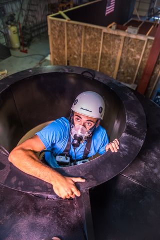 Garret Lovoy, studying nutrition and kinesiology during his senior year at Kansas State University, climbs out of a replica Orion space capsule used to test potential astronauts' health during an emergency escape.
