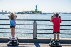 Kids looking at Statue of Liberty through paying binoculars from the Liberty State Park in Jersey city during summer day