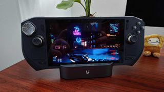 Zotac Zone handheld sitting on docking station with Cyberpunk 2077 gameplay on screen