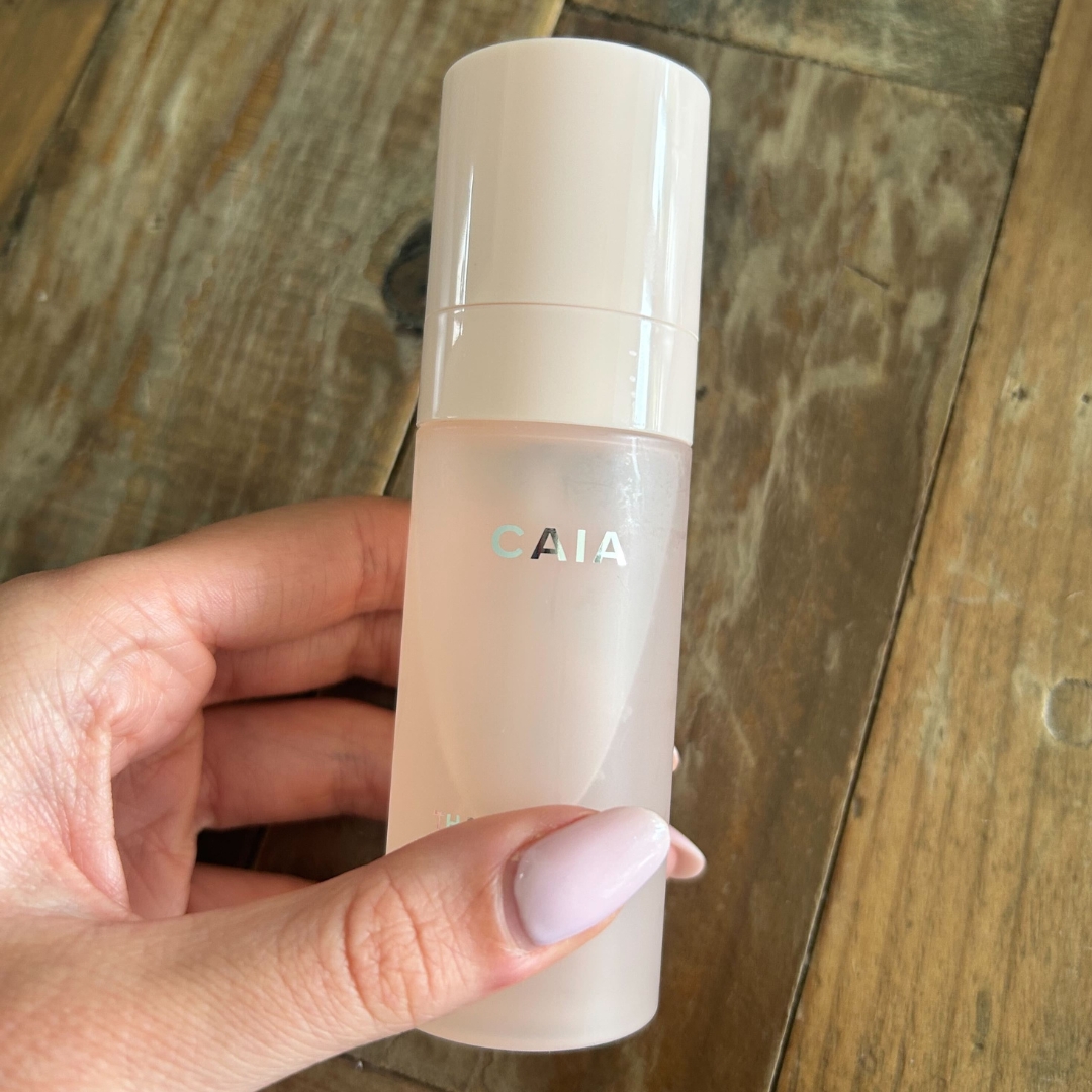 Hand holding the CAIA That Extra Hydration Hydrating Setting Spray