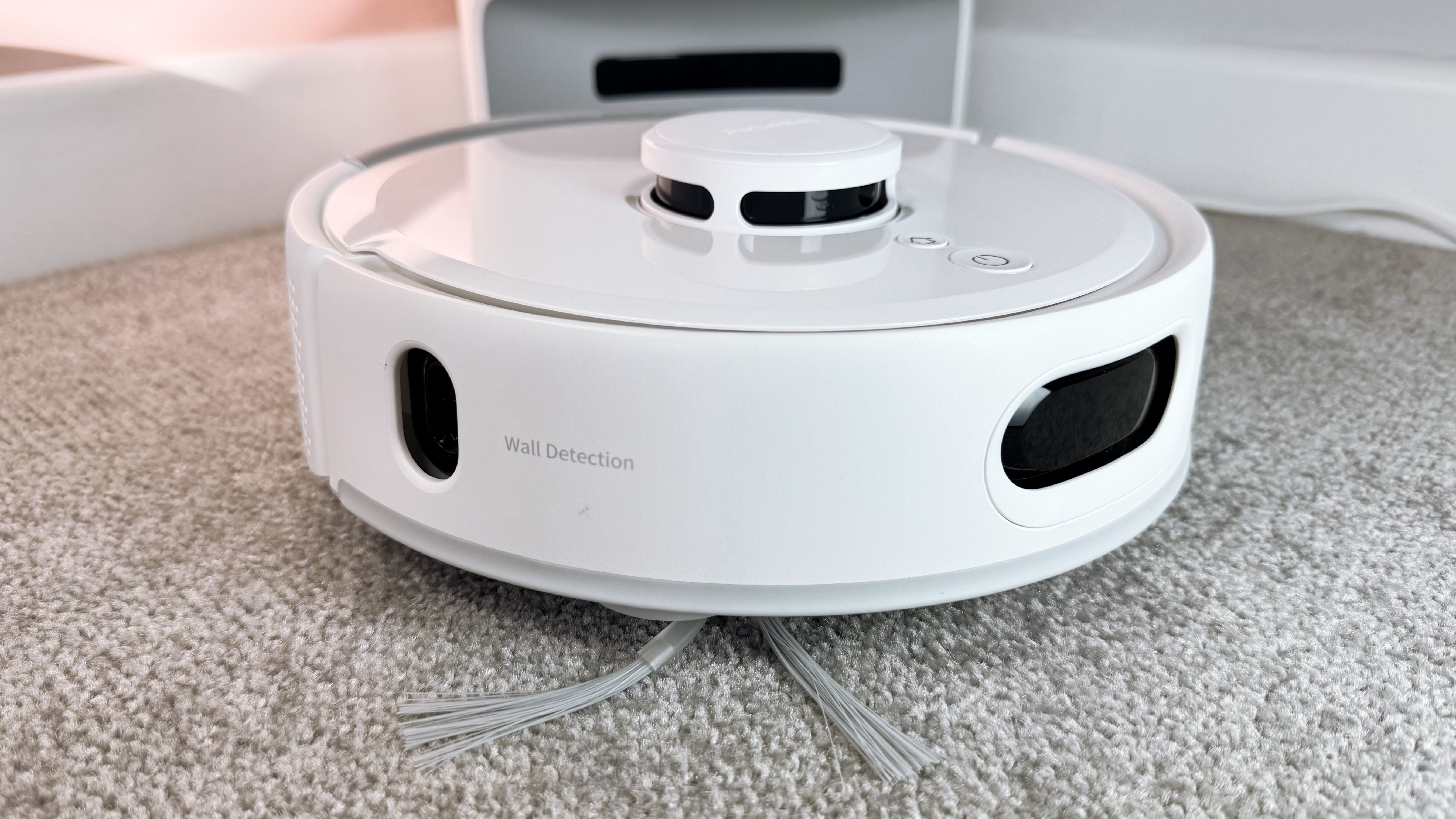 A side view of the SwitchBot K11 plus, showing the wall sensor and the rotating cleaning brush.