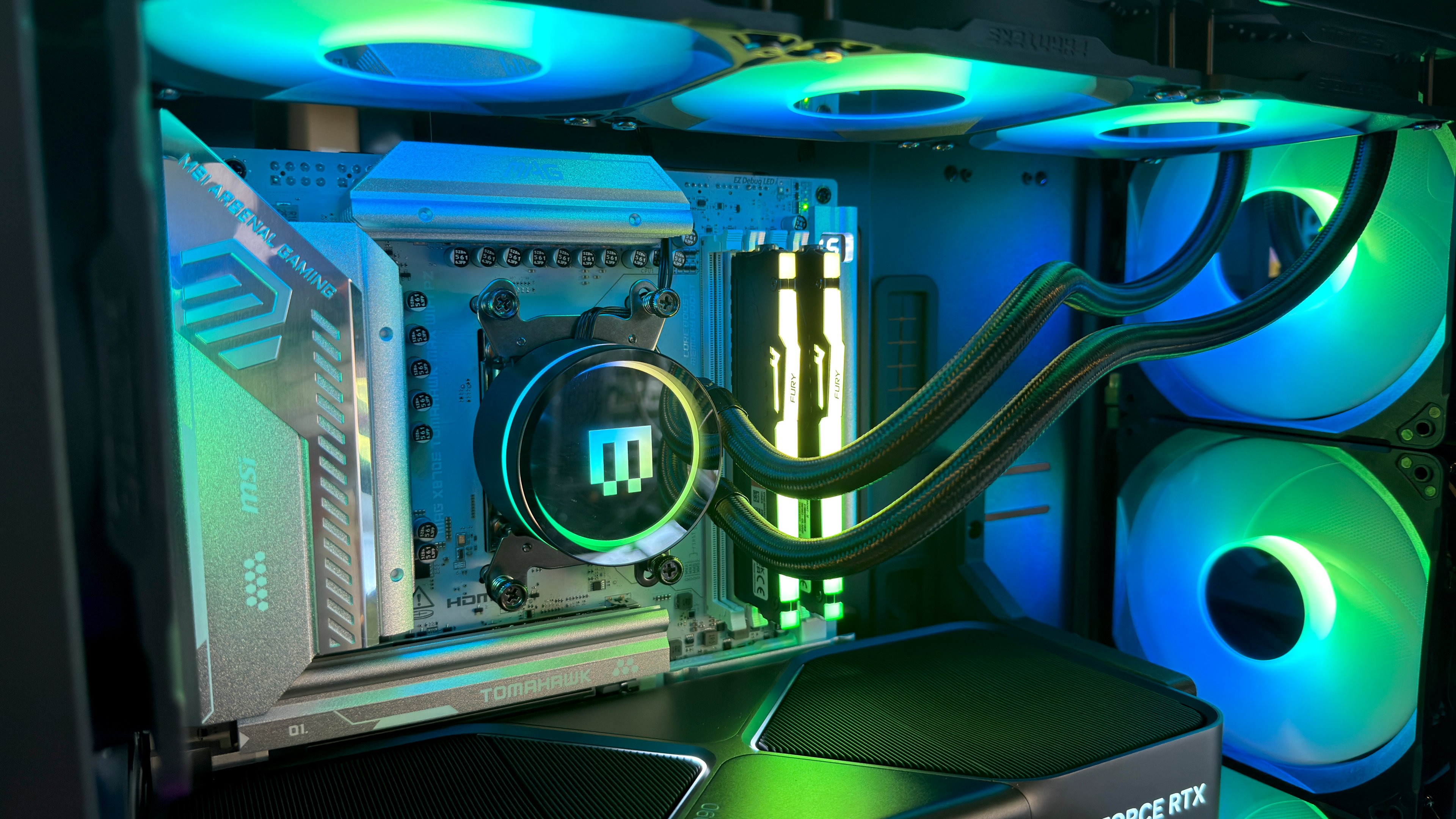 A close-up photo of the internal components of a Maingear MG-1 Mk.II gaming PC, showing the AIO cooler, fans, and RGB lighting
