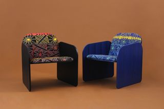 Two armchairs composed of vertical wooden panels framing an upholstered seat and back, printed with a pattern created by an Aboriginal textile artist