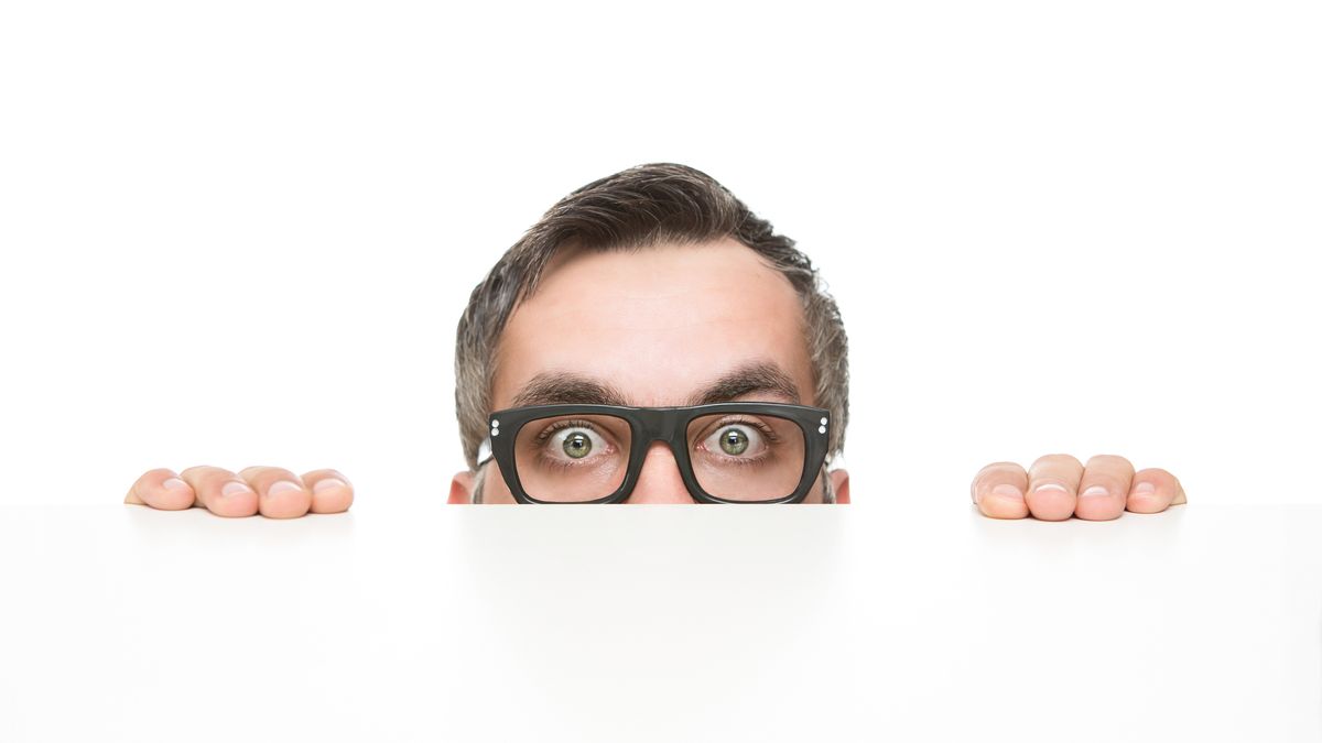 A man with glasses peering over a ledge.