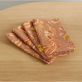 four folded orange napkins with a printed pattern