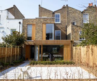 double storey brick and wood extension with large glazed window on ground floor and paved garden area