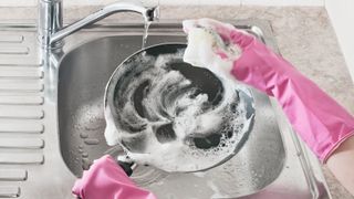 A pan being cleaned in a sink with soapy water