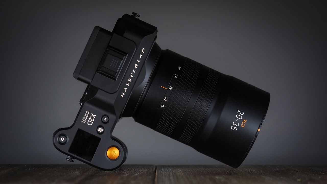 Hasselblad XCD 20-35E lens, moodily lit with subdued lighting, on a wooden surface