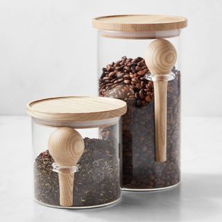 A large and small Williams Sonoma Hold Everything Coffee & Tea Stackable Canister with spoons. Each contains tea or coffee, and sit on a white countertop