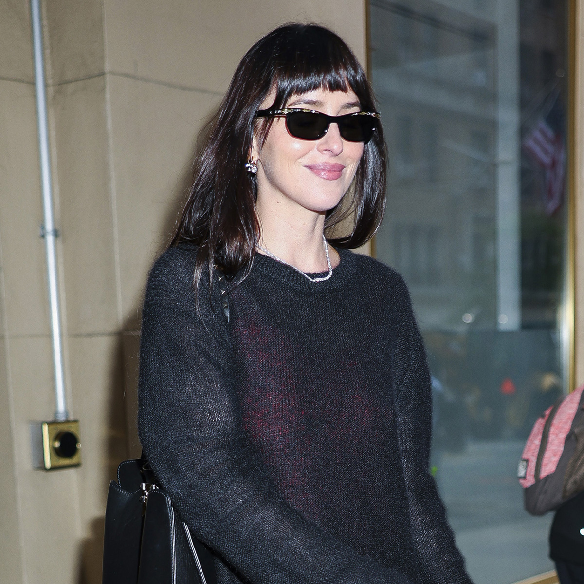 Dakota Johnson wearing a sheer black sweater, maxi skirt, and cream pointed-toe glove pumps in NYC