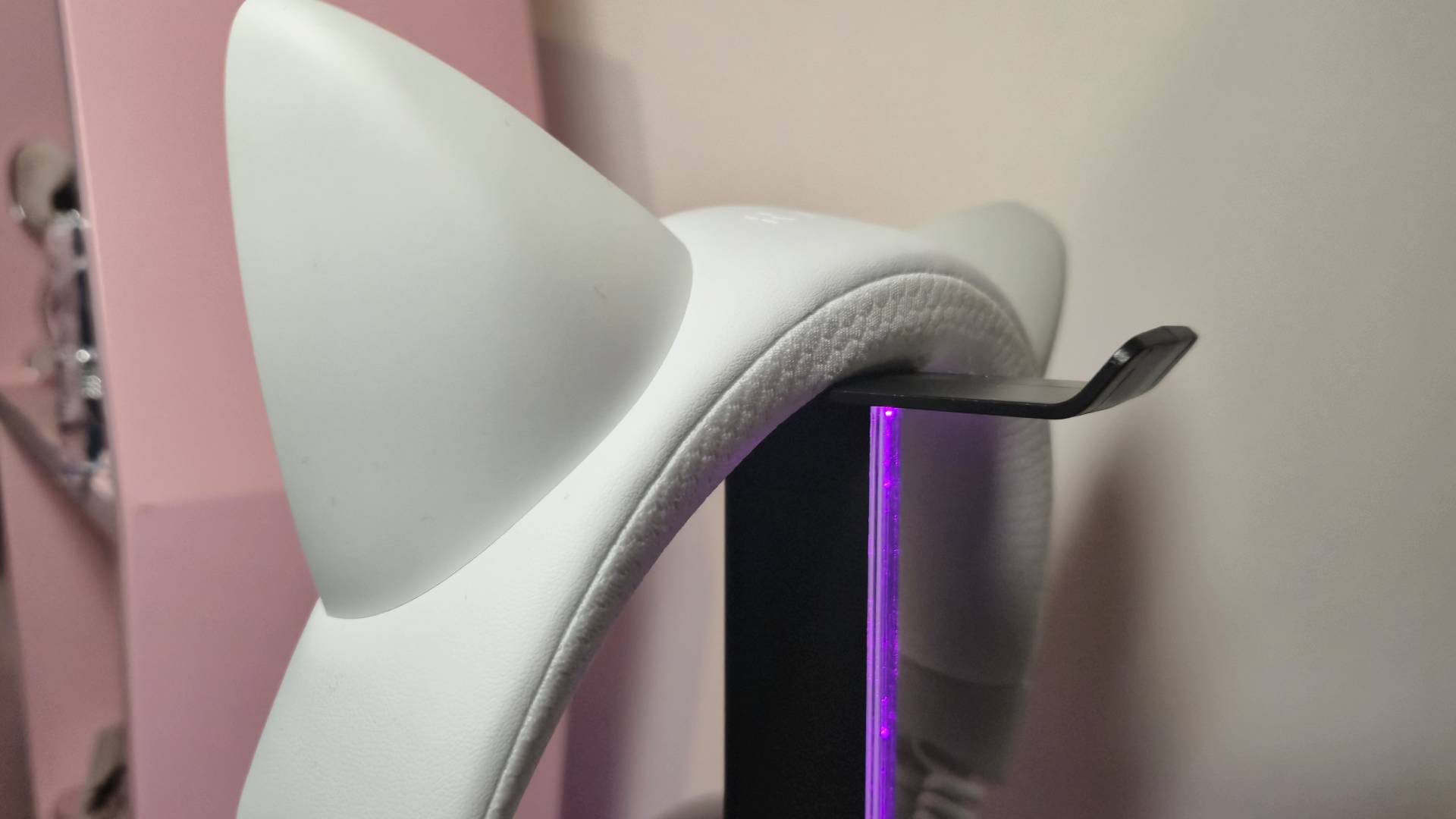 Photo of the Razer Kraken Kitty V3 Pro headset sitting on the headset rest of the charging stand.