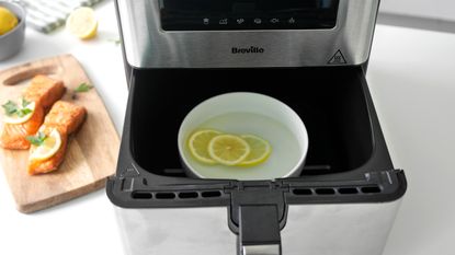 Bowl filled with water and lemons inside air fryer basket