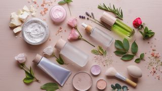 A collection of skincare products arranged with flowers and leaves