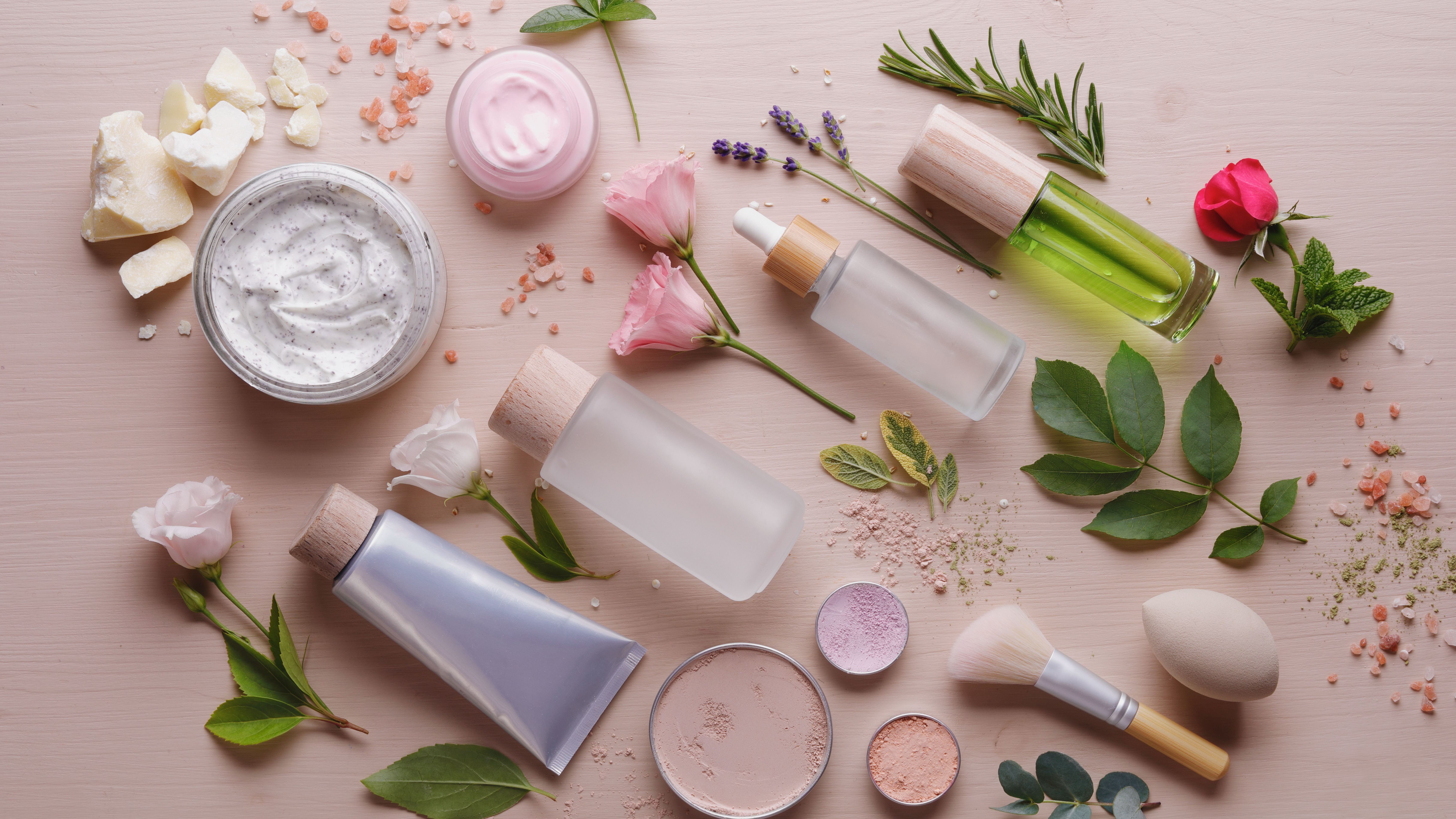 A collection of skincare products arranged with flowers and leaves