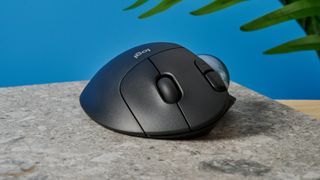 A black Logitech Ergo M575 ergonomic mouse with a teal trackball on the left side