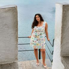 Plus size model wearing a Simply Be mini patchwork graphic dress leaning on a fence overlooking the ocean