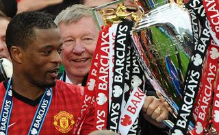 Manchester United's French defender Patrice Evra (L) and Manchester United manager Alex Ferguson (C) lift the Premier League trophy after the English Premier League football match between Manchester United and Swansea City at Old Trafford in Manchester, northwest England, on May 12, 2013. AFP PHOTO / ANDREW YATES RESTRICTED TO EDITORIAL USE. No use with unauthorized audio, video, data, fixture lists, club/league logos or "live" services. Online in-match use limited to 45 images, no video emulation. No use in betting, games or single club/league/player publications (Photo by ANDREW YATES / AFP) (Photo by ANDREW YATES/AFP via Getty Images)