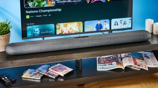 the bluesound pulse cinema soundbar photographed with a TV and the tom's guide blue background
