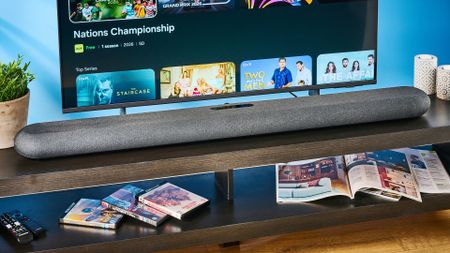 the bluesound pulse cinema soundbar photographed with a TV and the tom's guide blue background
