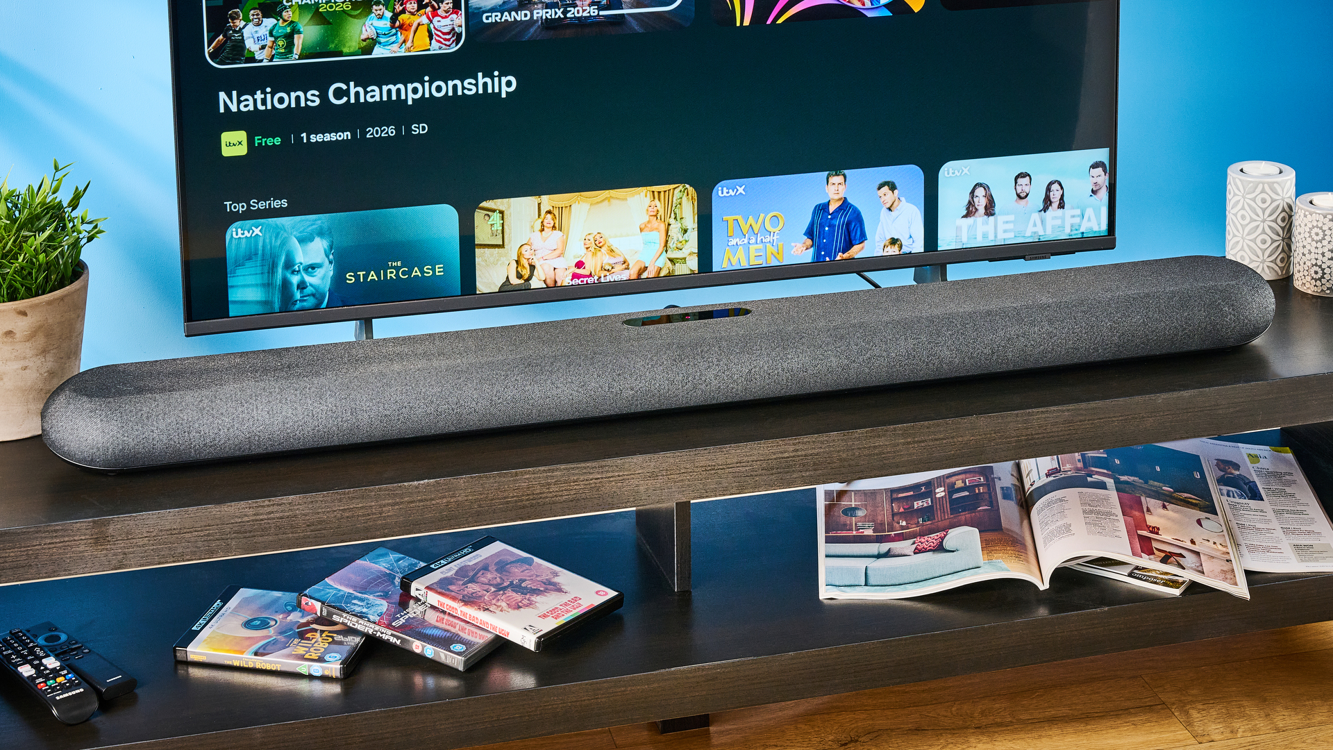 the bluesound pulse cinema soundbar photographed with a TV and the tom's guide blue background