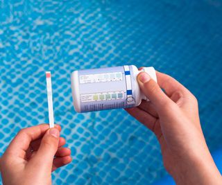 using test strips to check chlorine and PH levels in a pool