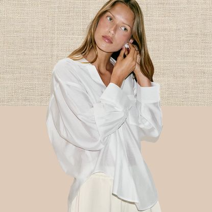 Zara model with wavy hair posing in a a chic summer 2026 outfit wearing an oversize white button-down shirt and beige lace-trim shorts