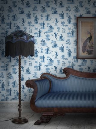 living room with blue toile style wallpaper, blue fringed lamp, artwork, blue stripe classic couch