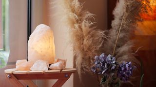 Himalayan salt lamp on a folding table in the hallway beside pampas grasses to show how to use crystals in the home