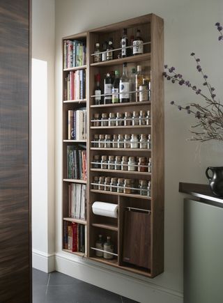 wall mounted spice storage with book shelves on one side, also shelving for drink, kitchen paper, chopping board