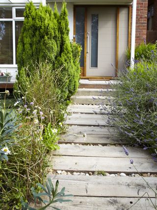 wood and stone pathway in a front garden leading to a painted front door