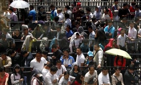 Customers wait in a fenced-off area outside the Beijing Apple Store Friday: Apple employees and customers reportedly got into a shoving match that broke the glass entrance door.