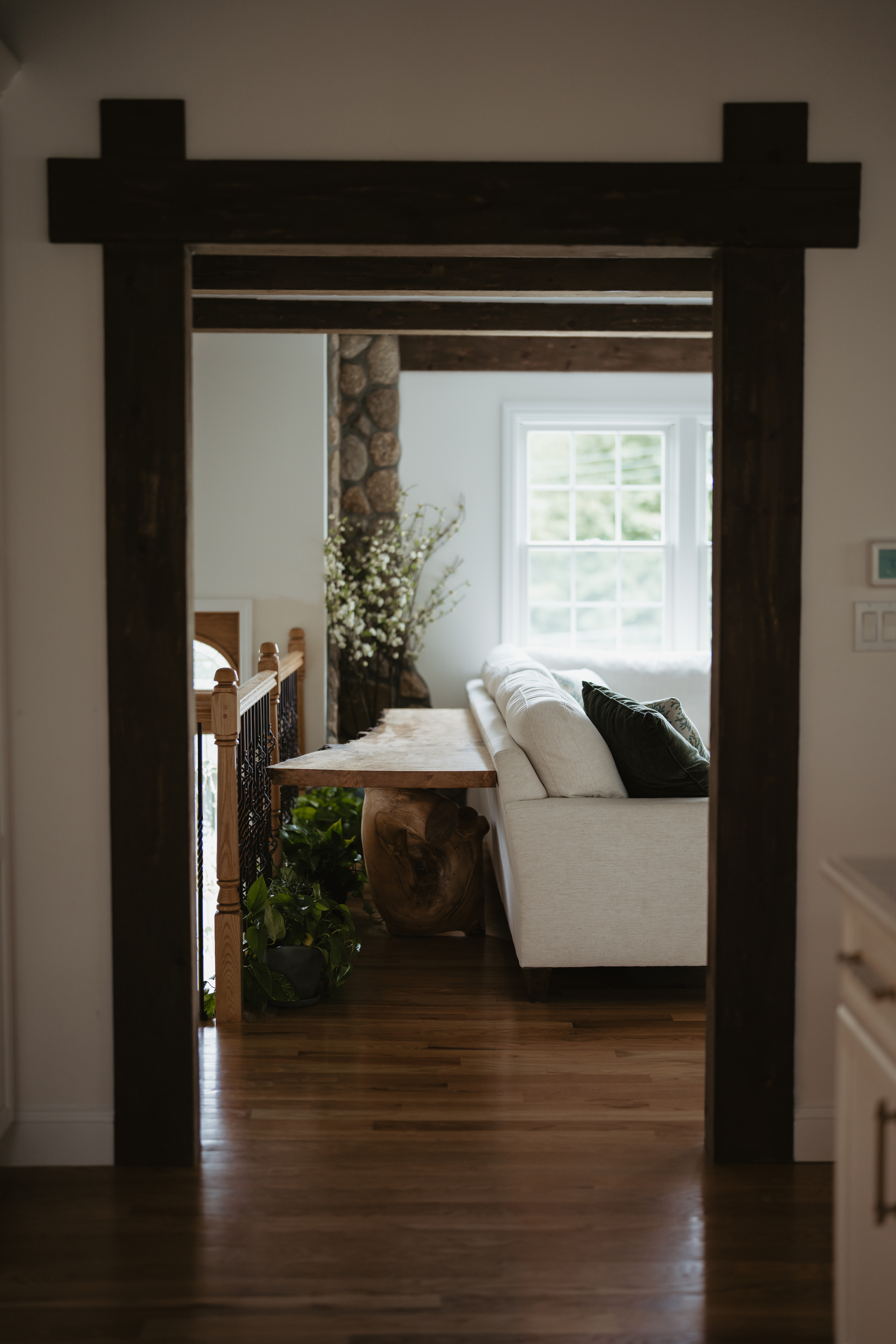 A view through a doorway into a living room with a white sofa and a wooden console table behind it