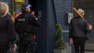 Shirley Carter walking off with a baseball bat with an armed police officer