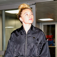 Florence Pugh wears a Prada nylon jacket with jeans and red embroidered boots at the airport.